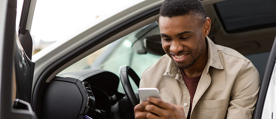 Man sitting in a car looking at a phone.