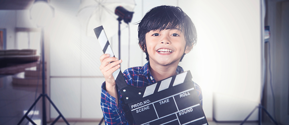 A child actor holding a clapboard.