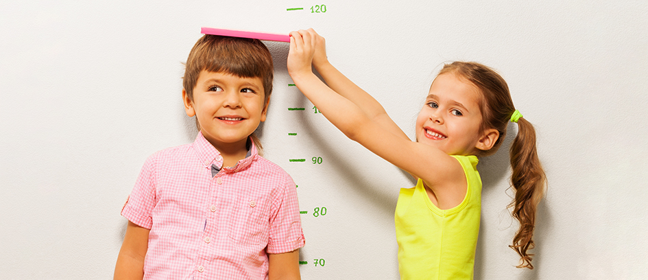 Two children measuring each child's sizes.