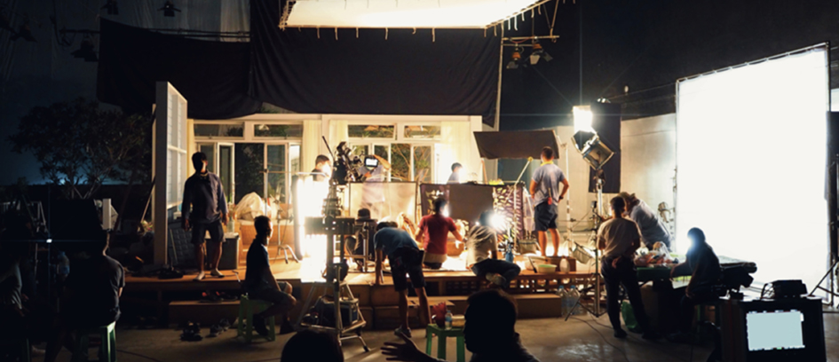 Crew setting up cinematic lighting on film set.