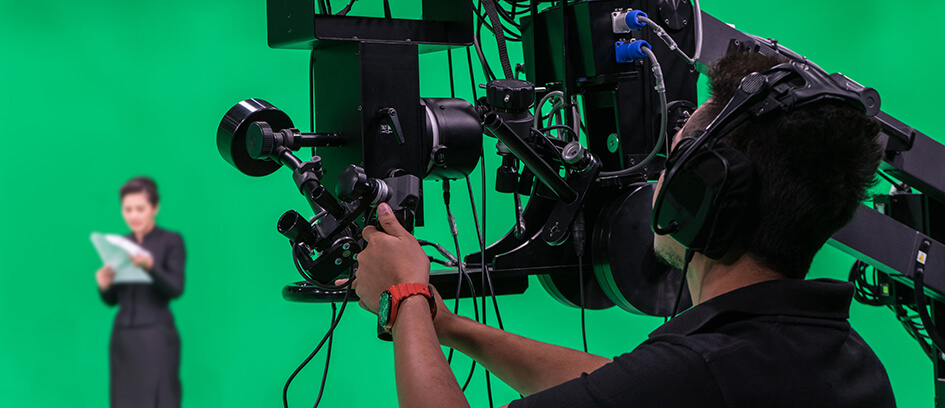 A camera operator and Stand-In in front of a green screen.