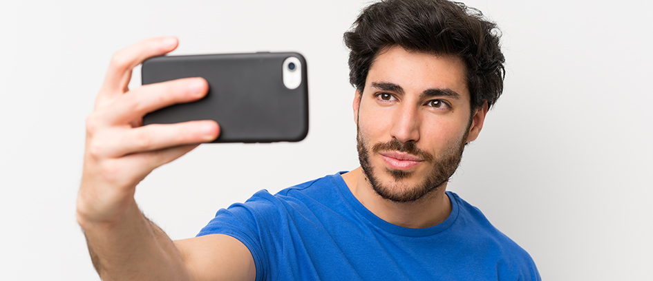 A man in a blue shirt practicing how to take a selfie.