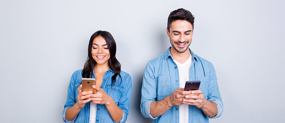 A man and woman looking at Central Casting messages on their phones.